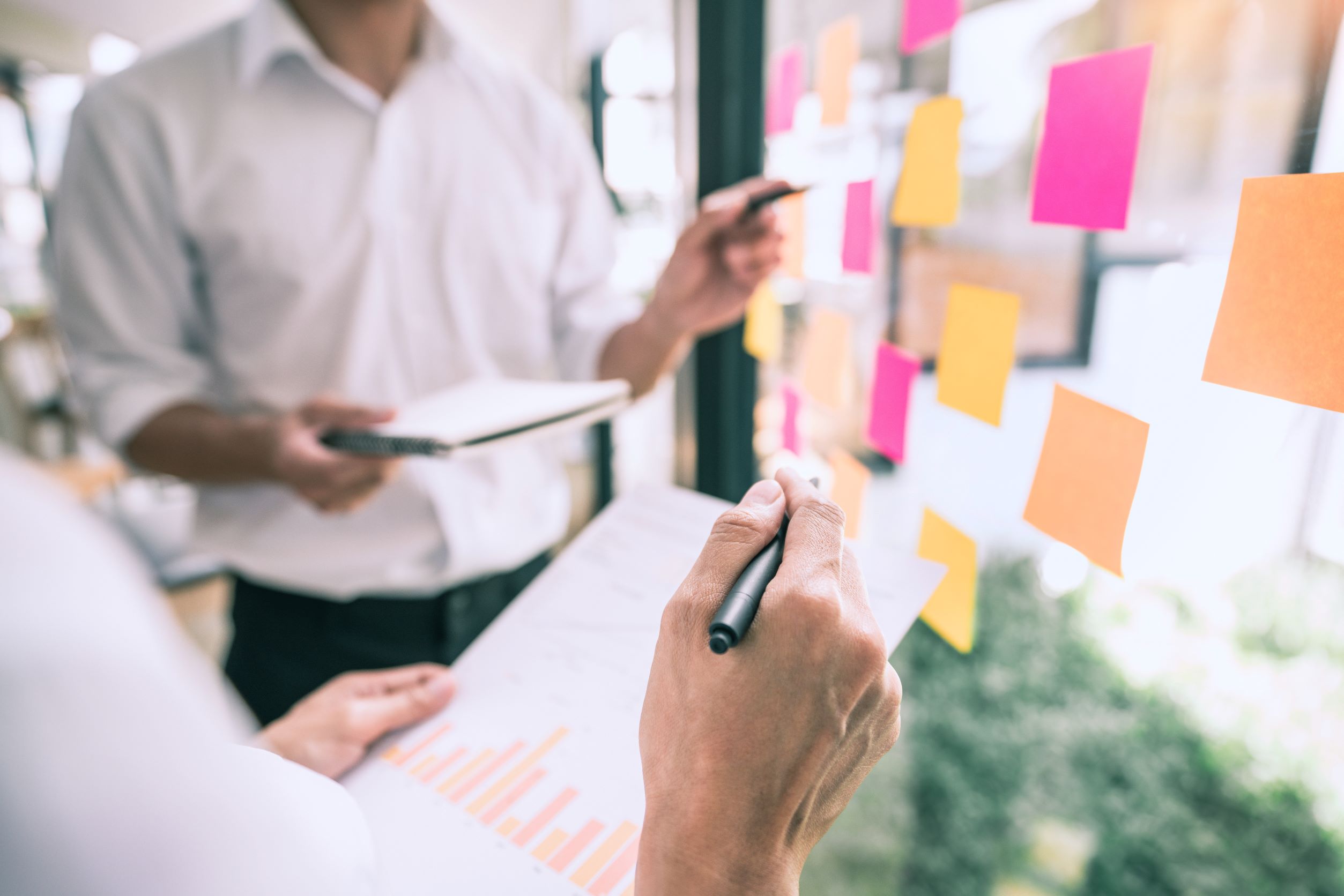 Business people meeting at office and use sticky notes on glass wall in office, diverse employees people group planning work together brainstorm